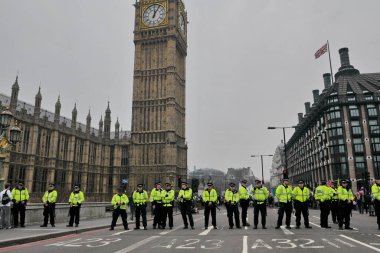 Police stand guard on Westminster Bridge during a large anti austerity rally on March 26, 2011 in London, UK. Police were on standby after violent clashes with anti-cuts protesters. clipart