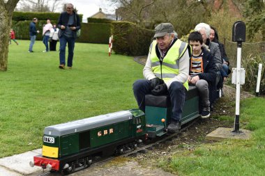 A driver and passengers ride on a miniature railway train on April 1, 2018 in Bulkington, UK.