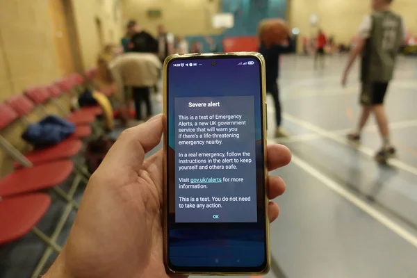 An emergency alert message is seen on a smartphone as people play basketball on April 23, 2023 in London, UK. The UK government tested its alert system sending out alerts phones across the country.