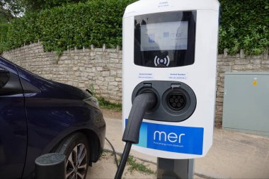 10 Haziran 2023 tarihinde Bournemouth, İngiltere 'de bir şehir merkezi caddesinde elektrikli araba şarj noktası görülmektedir. EV şarj istasyonlarına, motorcuların yanmalı motorlardan uzaklaşması nedeniyle yüksek talep var.