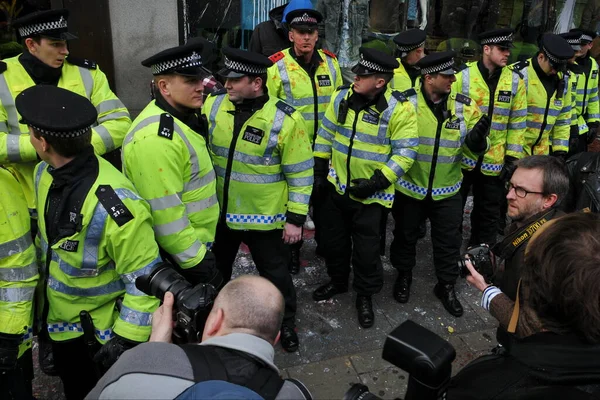 ジャーナリスト達は 2011年3月26日に英国のロンドンで開催された大規模な反政府集会の間 抗議者達によって攻撃された高層ビルを守るための線を形成する際に 警察を撮影しました — ストック写真