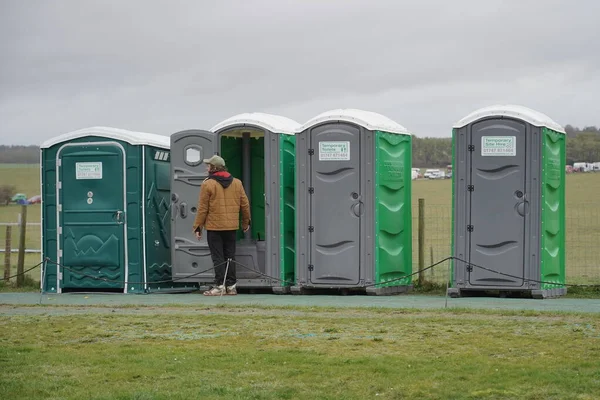 İnsanlar 21 Mart 2023 'te Amesbury, İngiltere' de portatif tuvalet kullanıyorlar. Taşınabilir tuvaletler genellikle gerekli hijyenik tesislere ev sahipliği yapmayan büyük açık hava etkinliklerinde kullanılır..