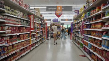 Müşteriler 31 Mayıs 2023 'te Bath, İngiltere' de bir Sainsbury süpermarketinde bir koridora bakıyorlar. Sainsbury, 2022 yılında 29,9 milyar geliri olan İngiltere 'nin ikinci büyük süpermarketi..