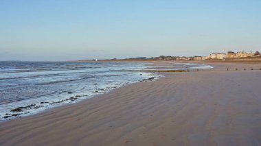 Somerset İngiltere 'de Burnham-on-Sea plajı olarak adlandırılan ılık akşam güneşiyle yıkanmış güzel sarı kumlu bir sahil manzarası.