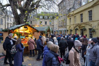 Tarihi Bath Abbey ve çevresindeki binalar 30 Kasım 2019 tarihinde Bath, İngiltere 'de bir şehir merkezi caddesinde görülmektedir. Somerset şehri, yılda 4 milyon ziyaretçi alan popüler bir seyahat merkezidir..