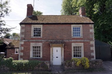 Güzel, sazdan yapılmış bir evin dış görünüşü ve bahçesi. İngiliz köyündeki sessiz bir sokakta kırmızı tuğlalı bir ev. 