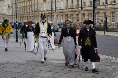 24 Temmuz 2020 'de Bath, İngiltere' de geleneksel kıyafet giyen insanlar şehir caddesi boyunca yürüyorlar. Somerset şehri Jane Austin 'in eviydi ve çoğu zaman drama için bir mekandır..