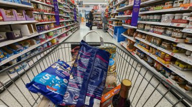 19 Ekim 2023 'te Londra, İngiltere' de Sainsburys süpermarket koridoru boyunca gıda ürünleriyle dolu bir yük arabası itilir. Sainsburys, Tesco 'dan sonra 1400 mağazası bulunan İngiltere' nin en büyük ikinci süpermarket perakendecisi..