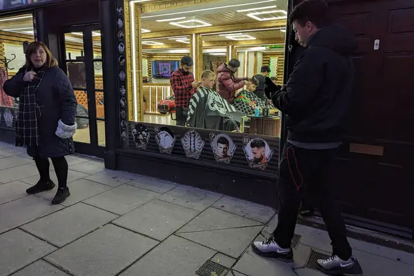 Stock image Men have their haircut at a barbers on a town centre street on November 25, 2023 in Warminster, UK.