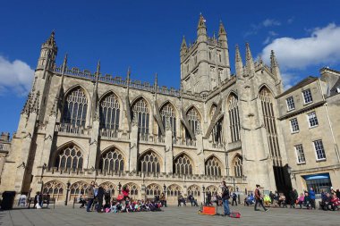 Turistler ve yerliler güneşli bir bahar gününde Bath Abbey 'in avlusunda 13 Mart 2018' de toplandılar..