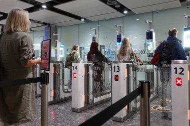 Uçak yolcuları 9 Eylül 2023 'te Londra, İngiltere' deki Heathrow Havaalanı 'ndaki otomatik pasaport kontrol kapılarından geçtiler. E-pasaportlar İngiltere 'ye bazı uluslara sürtünmesiz giriş imkanı sağlıyor.