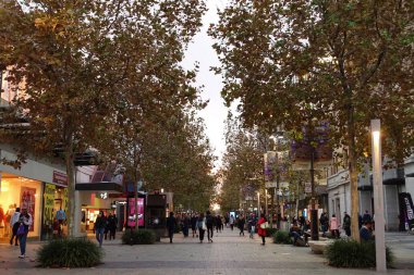 İnsanlar, 31 Mayıs 2018 'de Avustralya' nın Perth kentinde bir sonbahar akşamı şehir merkezinde yaprak kaplı bir alışveriş caddesi boyunca yürürler..   