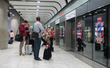 Havaalanı salonunda bavullu turistler bekliyor.