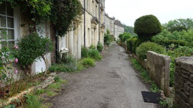 İngiltere 'nin Wiltshire şehrinde tarihi Bradford kasabası olarak bilinen güzel bir İngiliz kasabasındaki eski teraslı kır evlerinin yanından geçen taştan bir yolun manzarası.