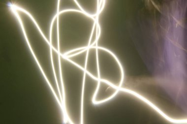 Siyah / yeşil arkaplanda uzun pozlu soyut renkli düzensiz çizgiler. Hafif resim fotoğrafçılığı. Üst üste koymak için düzensiz desenli ışıklar