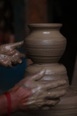 Çömlekçi, yumuşak renkli kilden yapılmış bir çömlekçi çarkı üzerinde çalışıyor. El ve ekipman ile eski tarz kil kapları.