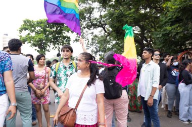 Chennai, Tamilnadu India - 25 Haziran 2023: Gururlu gökkuşağı bayrağı ve bayrağı taşıyan bir grup insanın dikiz görüntüsü.