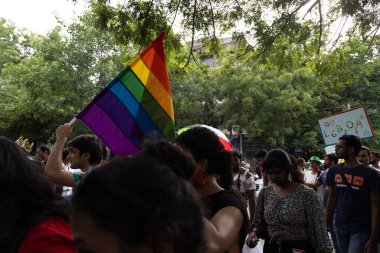 Chennai, Tamilnadu India - 25 Haziran 2023: Gururlu gökkuşağı bayrağı ve bayrağı taşıyan bir grup insanın dikiz görüntüsü.