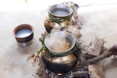 celebrating Traditional Thai Pongal festival to sun god with pot, lamp,wood fire stove, fruits and sugarcane. Making Sakkarai or sugar pongal and ven pongal in sand stove in traditional method. clipart