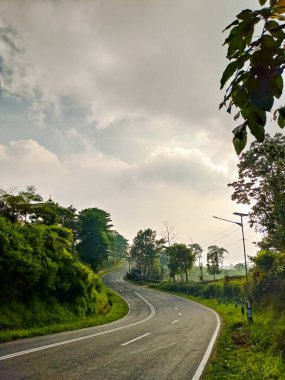 Golden hour view of long and winding road in the hills during a cloudy day