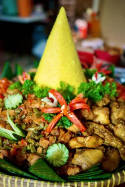 Nasi Kuning 'in (aromatik baharatlar ve hindistan cevizi ile Endonezya sarı pirinci) yan yemekleri (sambal, empal, tempe orek, sambal goreng ati, ve ayam kuning) ile bütünleşmiş hali. Güneydoğu Asya yemeği.