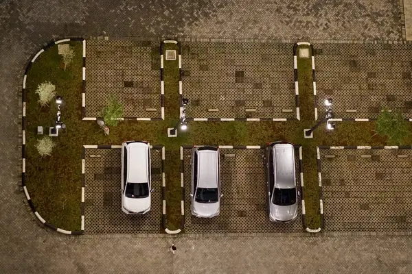 An apartment outdoor parking space filled with 3 cars parralel to each other.