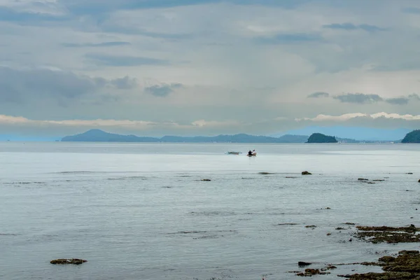 This photo captures the essence of the Philippines, with a traditional wooden boat bobbing on crystal-clear turquoise waters, surrounded by lush green tropical foliage. 