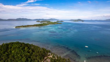 Fotoğraf, berrak suları ve kıyıya vuran hafif dalgalarla sakin bir sahilin nefes kesici görüntüsünü yakalıyor. Sonsuz altın kum taneleri güneş şemsiyeleri, plaj sandalyeleri ve palmiye ağaçları ile kaplıdır.. 
