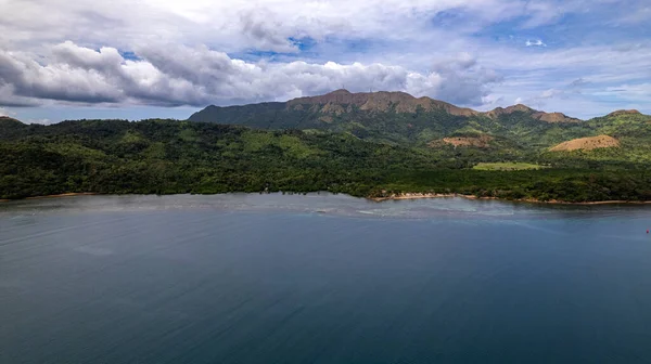 stock image The photo captures the breathtaking beauty of a tropical jungle or mountain range. Lush green foliage dominates the foreground, while in the distance, towering peaks or mist-shrouded mountains rise majestically against the sky. The tranquil scene is 