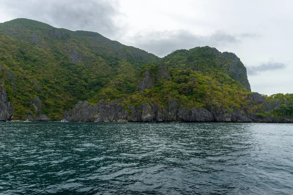 この写真は フィリピンの驚くほど険しい海岸線を示しています 一連の岩の切り株は 波の重なりによって滑らかに身に着けられ 水平線に伸び ターコイズブルーの海はそれらの周りを旋回します — ストック写真