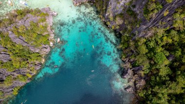 Bu fotoğraf bir Filipinler lagününün ruhani güzelliğini yansıtıyor. Su, kayalık bir uçurum ve yeşil bir orman tarafından çerçevelenmiş turkuazın mükemmel bir gölgesidir. Sakin yüzey sadece ara sıra kano ya da raketlerle kırılır, ziyaretçiler gibi. 