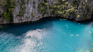Bu fotoğraf bir Filipinler lagününün ruhani güzelliğini yansıtıyor. Su, kayalık bir uçurum ve yeşil bir orman tarafından çerçevelenmiş turkuazın mükemmel bir gölgesidir. Sakin yüzey sadece ara sıra kano ya da raketlerle kırılır, ziyaretçiler gibi. 