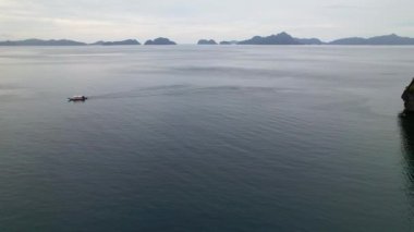 Filipinler 'deki bir teknenin insansız hava aracı görüntüleri. Güzel bir sahile ya da kayalık bir sahile yakın sazdan çatılı canlı bir tropikal tekne görebiliyoruz..