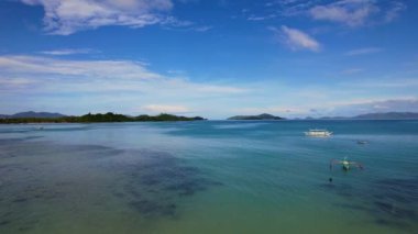 Filipinler 'deki bir teknenin insansız hava aracı görüntüleri. Güzel bir sahile ya da kayalık bir sahile yakın sazdan çatılı canlı bir tropikal tekne görebiliyoruz..