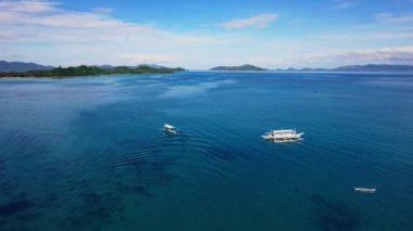 Filipinler 'deki bir teknenin insansız hava aracı görüntüleri. Güzel bir sahile ya da kayalık bir sahile yakın sazdan çatılı canlı bir tropikal tekne görebiliyoruz..