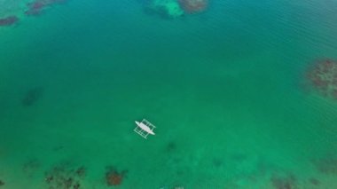 Filipinler 'deki bir teknenin insansız hava aracı görüntüleri. Güzel bir sahile ya da kayalık bir sahile yakın sazdan çatılı canlı bir tropikal tekne görebiliyoruz..