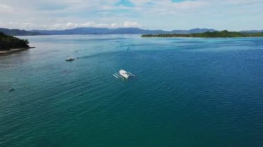 Filipinler 'deki bir teknenin insansız hava aracı görüntüleri. Güzel bir sahile ya da kayalık bir sahile yakın sazdan çatılı canlı bir tropikal tekne görebiliyoruz..