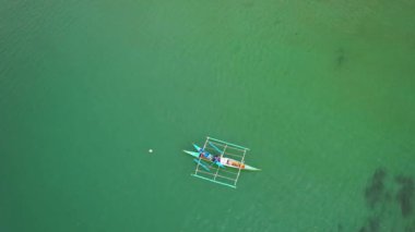 Filipinler 'deki bir teknenin insansız hava aracı görüntüleri. Güzel bir sahile ya da kayalık bir sahile yakın sazdan çatılı canlı bir tropikal tekne görebiliyoruz..