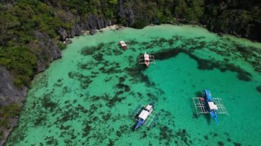 Filipinler 'deki bir teknenin insansız hava aracı görüntüleri. Güzel bir sahile ya da kayalık bir sahile yakın sazdan çatılı canlı bir tropikal tekne görebiliyoruz..