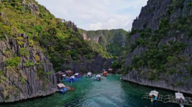 Filipinler 'deki bir teknenin insansız hava aracı görüntüleri. Güzel bir sahile ya da kayalık bir sahile yakın sazdan çatılı canlı bir tropikal tekne görebiliyoruz..
