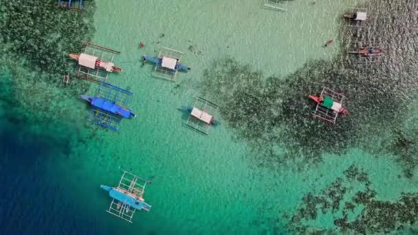 フィリピンのボートのドローン映像 私たちは 茅葺き屋根の活気ある熱帯ボートが美しいビーチや岩場の海岸の近くに停泊しているのを見ることができます — ストック動画