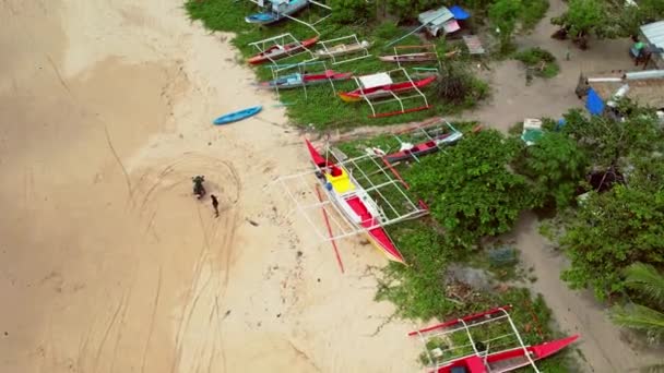 フィリピンのボートのドローン映像 私たちは 茅葺き屋根の活気ある熱帯ボートが美しいビーチや岩場の海岸の近くに停泊しているのを見ることができます — ストック動画