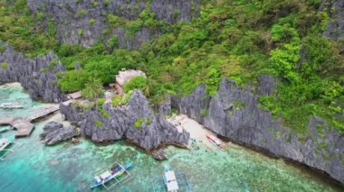 İnsansız hava aracı görüntüleri. Filipinler 'in ana deneği olarak göl ve körfezin havadan görünüşü. Etrafı kayalarla, ormanlarla ve park halindeki teknelerle çevrili küçük limanlardan uzaklaşın. Yoğun mavi bir göl görüyoruz..