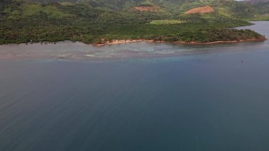 Coron Filipinleri 'ndeki sahil şeridinin insansız hava aracı görüntüleri. Güzel bir yemek tarifi, mavi sular, sahil ve ormanla sahil şeridine yaklaşmak için dolly hareketi yapıyoruz..