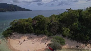 Coron Filipinleri 'nde bilinmeyen bir turistin olduğu küçük bir adanın insansız hava aracı görüntüleri. Uzaktaki kucaklaşma adasının ve mavi suların geniş manzarasını görüyoruz..