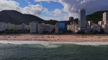 Rio de Janeiro Brezilya 'daki Copacabana Sahili' nin insansız hava aracı görüntüleri. Video, sahile ve şehre bakarak başlıyor ve sahili ve şehri filme almak için bir pist hareketi yapıyor..