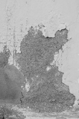 Bir sürü çatlağı ve deliği olan bir duvar. Duvar gri ve beyaz.