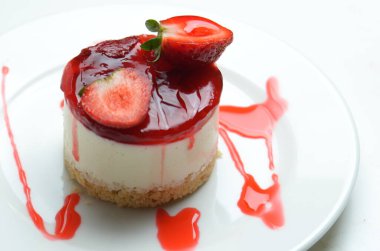 Çilek jelatiniyle kaplanmış ve çilekle süslenmiş cheesecake..