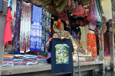 Bangkok, Tayland. 21 Kasım 2014: Tayland 'ın en büyük yüzen pazarlarından birinde bir satıcı ürünlerini ziyaretçilere gösteriyor.