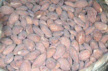 Şehir merkezindeki büyük bir markette baharat pazarında saman sepetinde tuzlanmış badem yığını..